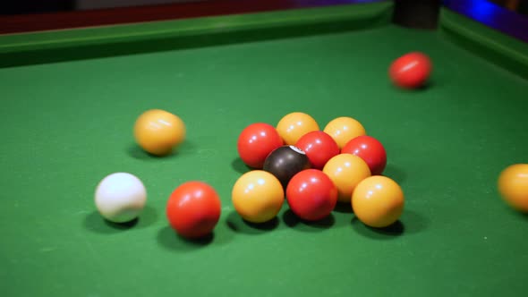 Close up of a pool break. A man hits the white ball into a triangle of pool balls