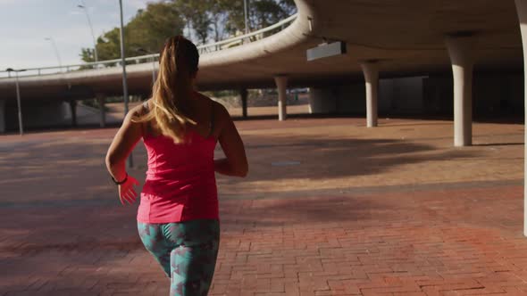 Caucasian woman running under a bridge