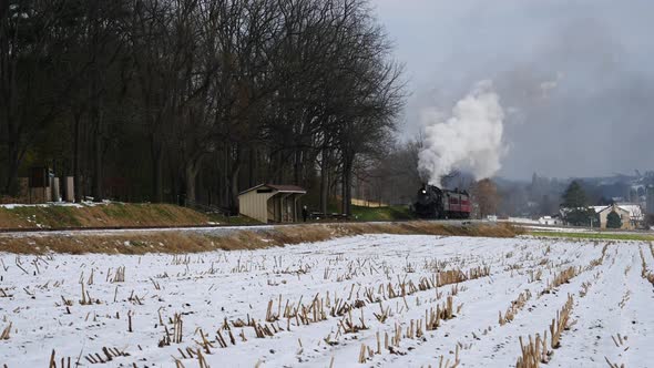 Steam Engine and Passenger Cars Puffing Along Amish Farm Lands After the First Snow of the Season