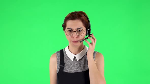 Portrait of Funny Girl in Round Glasses with Headset Helping with Customer Service. Green Screen