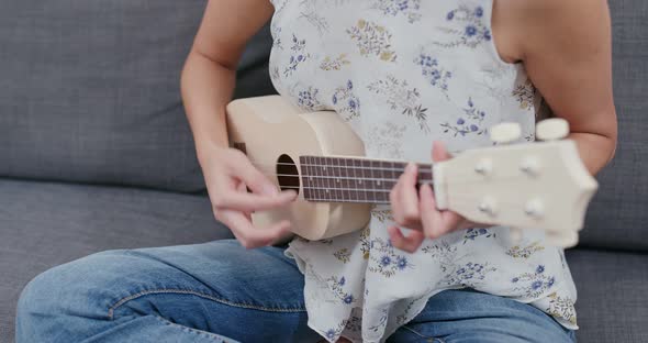 Woman play ukulele at home