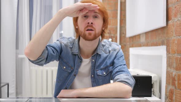 Searching Gesture by Redhead Beard Man Sitting in Office