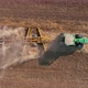 Slowmo - Green tractor plowing an agricultural field leaving big cloud of dust, 4k aerial drone view - VideoHive Item for Sale