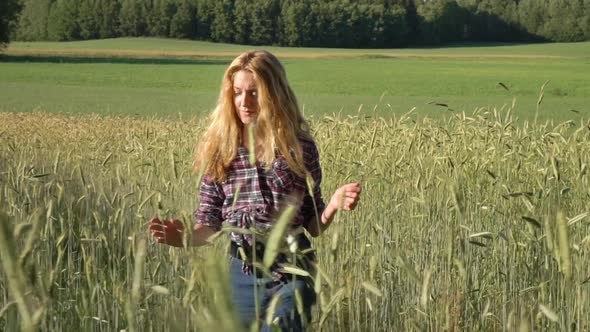 Country Girl Farmer with Golden Hair Wearing a Checked Shirt Walking in Rye Field