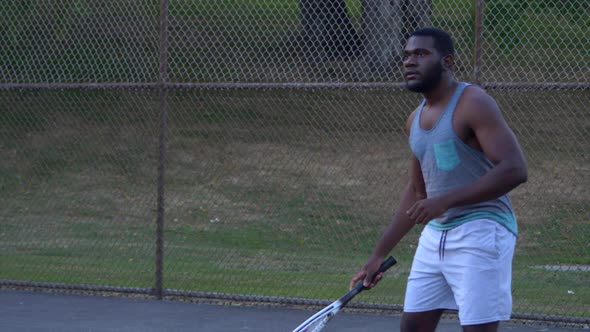 Athletic African American Tennis Player returns to the Baseline before hitting a forehand that doesn