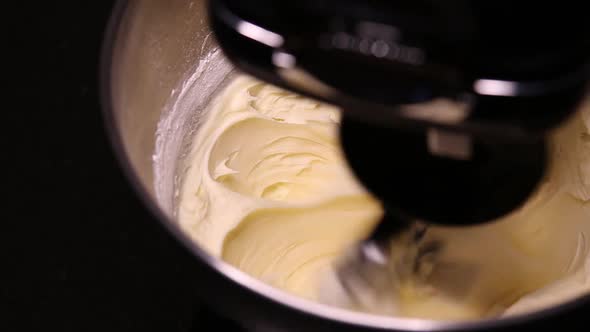 Close up shot of buttercream icing being whipped in a stand mixer.