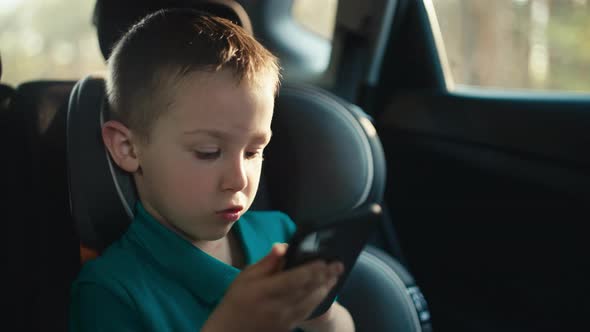 A Child Plays Games on the Phone While Traveling By Car