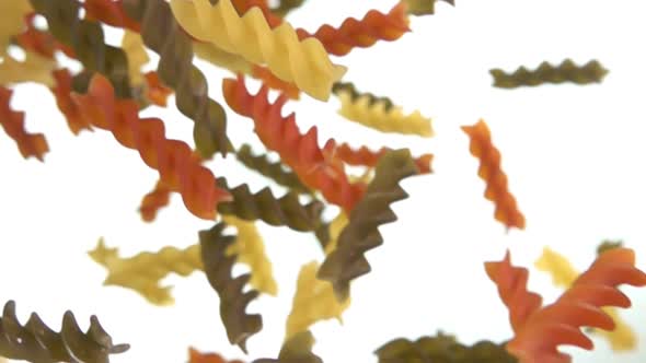 Closeup of the Colored Pasta Fusilli Falling Diagonally on a White Background