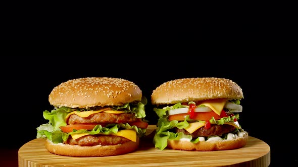 Two Craft Beef Burgers on Wooden Table Isolated on Dark Grayscale Background.