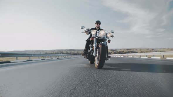 Confident Biker in Black Leather Jacket Helmet and Glasses Rides Along the Highway on Cool