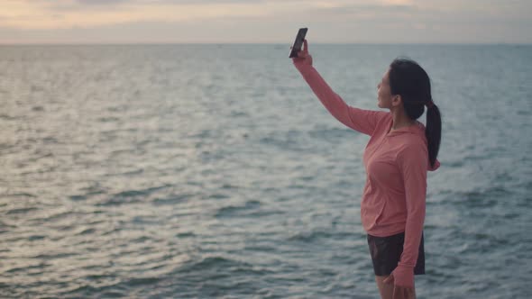 A beautiful sports girl using a smartphone takes a selfie after running a workout.