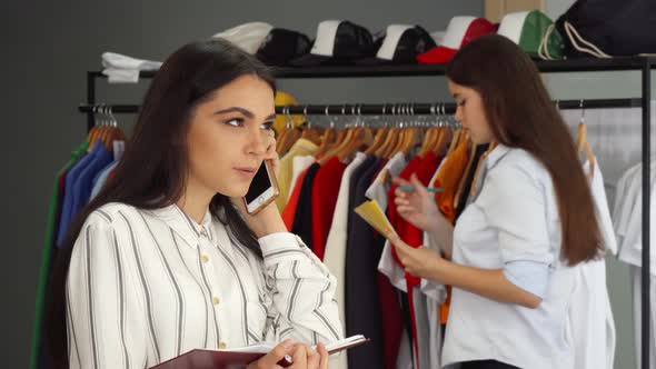 Beautiful Female Shop Assistant Talking on the Phone, Working at the Clothing Store