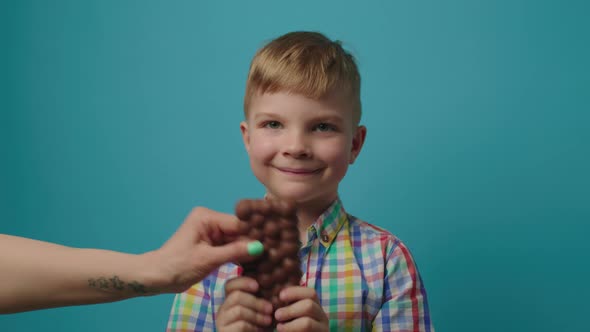 Mom's Hand Taking Away Chocolate Bar Form Kid's Hands and Giving Son Healthy Food Salad
