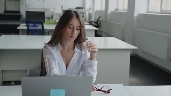 Sitting Woman Takes Off Her Red Glasses