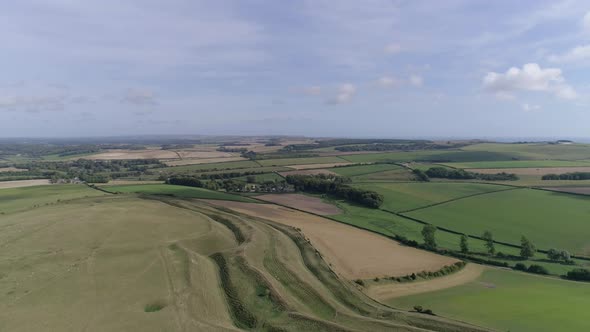 High up aerial tracking forward over Maiden Castle looking south, Sea is just visible on the horizon