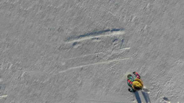 Happy Girl Falls Down at Snow To Create a Snow Angel. Aerial View.