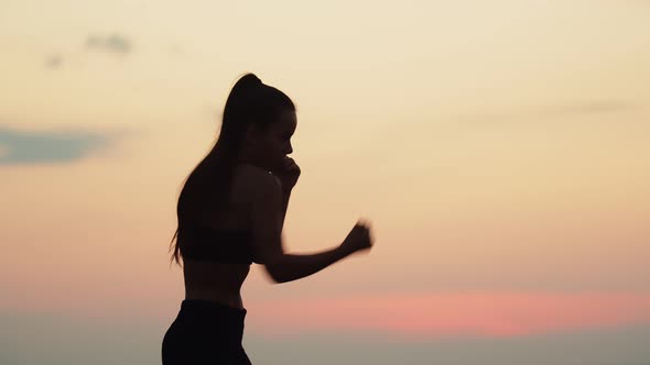 Woman Conducts Combination of Boxing Punches the Air in Nature Background Sky Side View