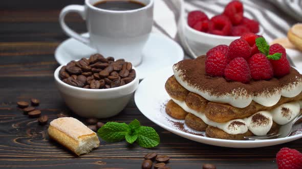 Portion of Classic Tiramisu Dessert with Raspberries, Savoiardi Cookies and Cup of Espresso Coffee