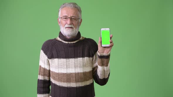 Handsome Senior Bearded Man Wearing Warm Clothing Against Green Background