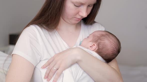 Little Newborn Baby Boy Sleeping with Baby Dummy on Mother Hands at Home Mom Puts Baby to Sleep