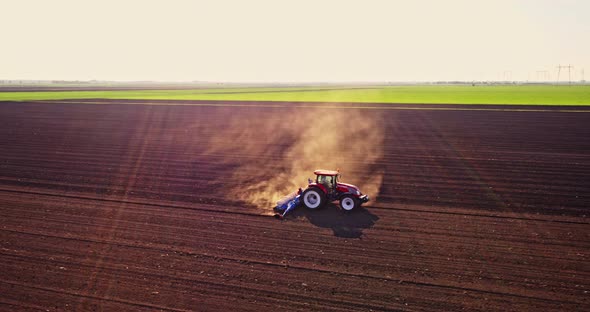 Farmer seeding soybeans with tractor on plowed field