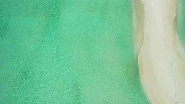 Beautiful fly over abstract shot of a white sandy paradise beach and turquoise sea background in col