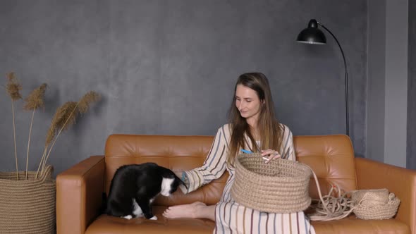 Woman Knitting Crocheting at Home with her Cat sitting on the Couch, Copy Space, Hobby and Passion