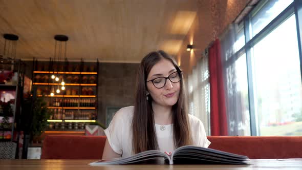 Pretty Girl Reading the Menu and Making an Order