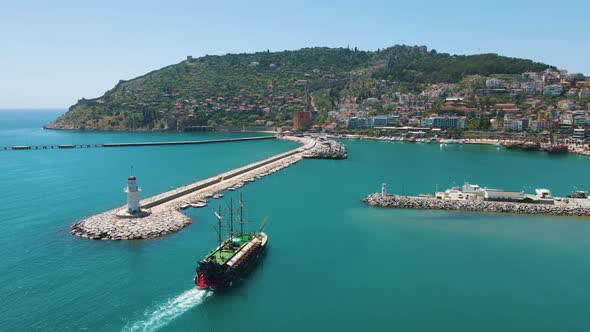 Excursion ship enters the marina of Alanya. Kizil Kule or Red Tower and port aerial panoramic view i