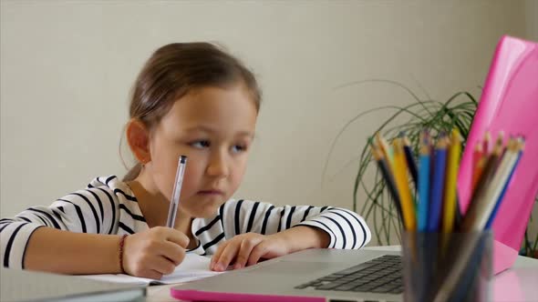 Little Child Girl is Studying Online at Home