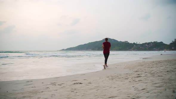 Young Healthy Woman Jogging at the Beach at the Sunrise Time