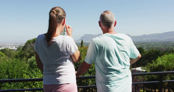 Rear view of caucasian senior couple drinking coffee and talking to each other in the balcony at hom