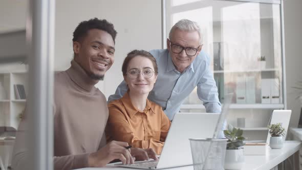 Multiethnic Young Associates and Senior Mentor Posing Together in Office