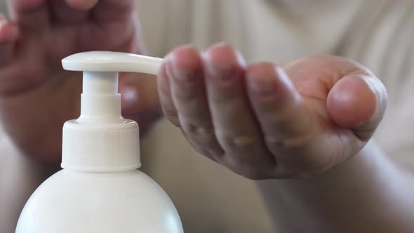 A Woman Treats Her Hands with an Antiseptic in a Cafe