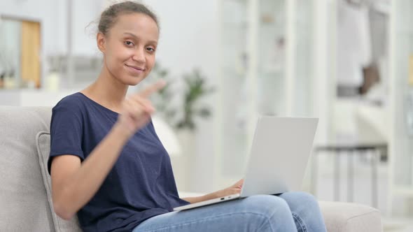 Excited Young African Woman with Laptop Pointing at the Camera 