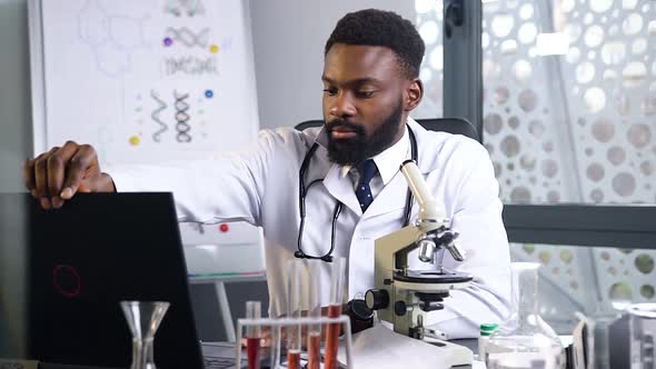 African American Doctor Starting to Work with Microscope and Computer in the Modern Medical Office