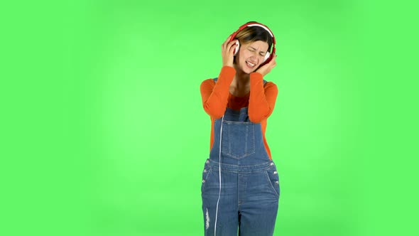 Cheerful Girl Dancing and Enjoys Music in Big Red Headphones. Green Screen