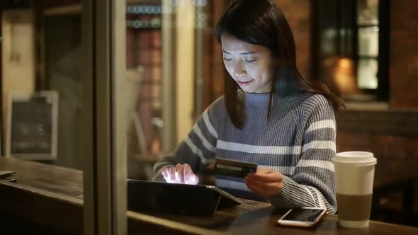 Woman using tablet pc at coffee shop at night