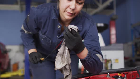 Female mechanic cleaning equipment of the car with a cloth at a car service station