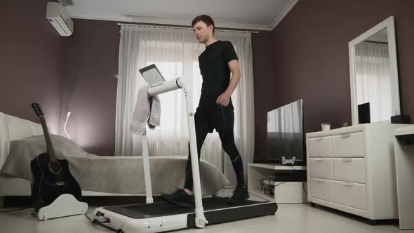Young motivated man is doing morning fitness exercises on treadmill