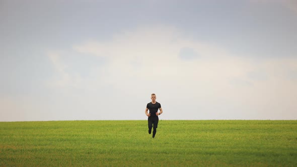 A Sportsman is Running Across the Green Grass and Looking at the Camera