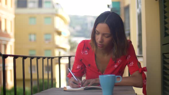 A woman writing in a journal diary traveling in a luxury resort town in Italy, Europe.