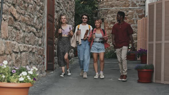 Four Diverse Friends Walking Along Narrow Brick Road