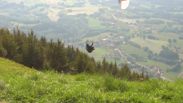 Paraglider taking off the side of a grass-covered mountain.