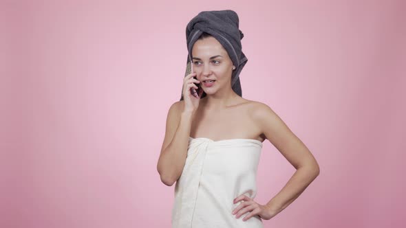 Woman with Towel on Her Head Talking on Phone, Isolated on Pink Background