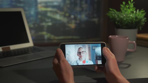 Woman Holding Smartphone with Video Calling to the Blonde Female Doctor in Glasses