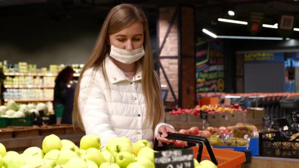 Young woman in a medical mask buys fruit. Self-isolation mode announcement 