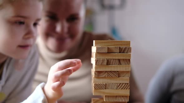 Cheerful cute family plays board games and builds a tower out of wooden cubes