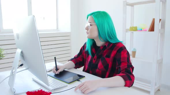 Young Graphic Designer with Color Hair Working on Computer Using Tablet