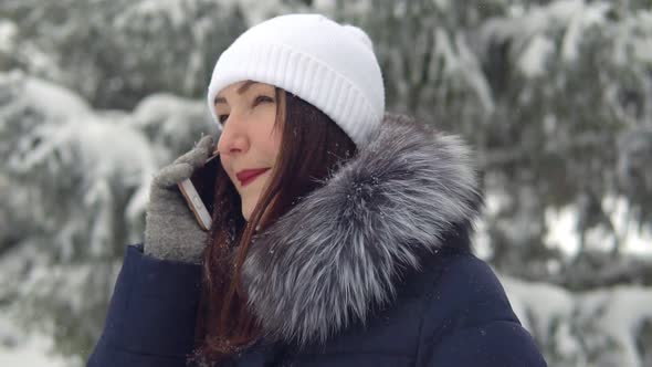 Young Woman Is Talking on the Phone in the Winter Forest